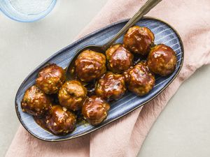 Honey garlic pork meatballs in a bowl with a serving spoon