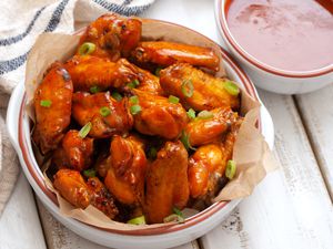 Classic Buffalo wings in a bowl with sauce nearby