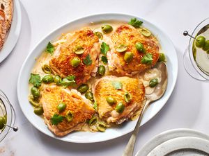 A platter of three martini chicken, topped with green olives and parsley, served with crusty bread and dirty martinis.