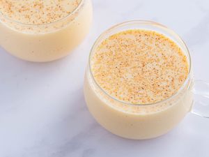 Eggnog with brandy, bourbon, or rum recipe; eggnog in a clear cup on a white marble counter