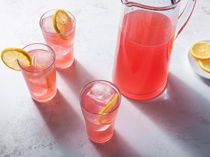 Pink lemonade in glasses and in a pitcher, garnished with lemons 