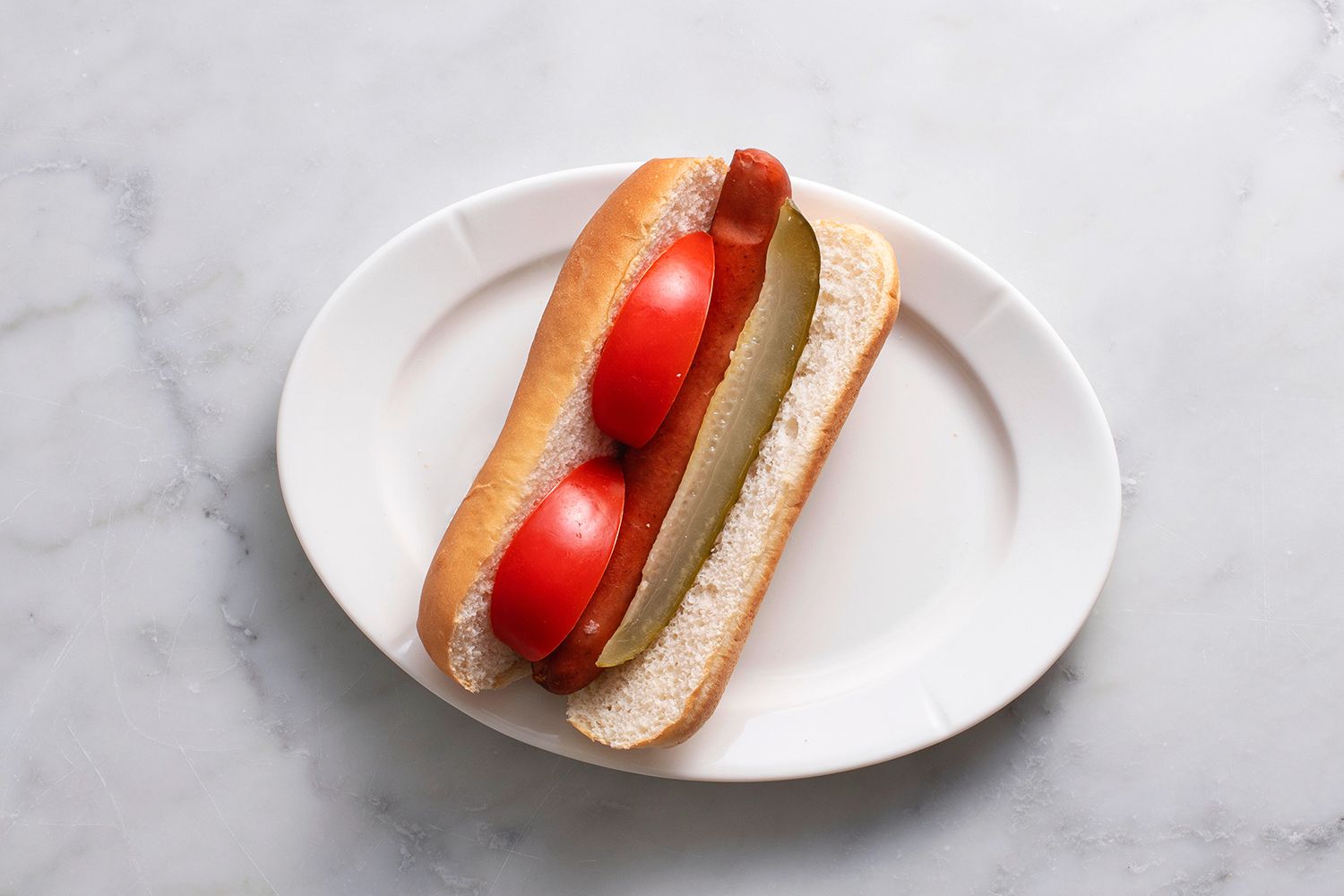 A hot dog with tomato and pickle