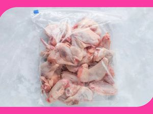 A Ziploc bag filled with frozen chicken wings on a white background
