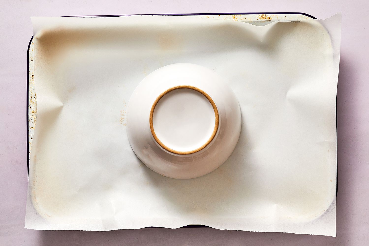 ceramic bowl inverted on a parchment lined baking sheet