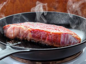 A steak searing in a cast-iron skillet