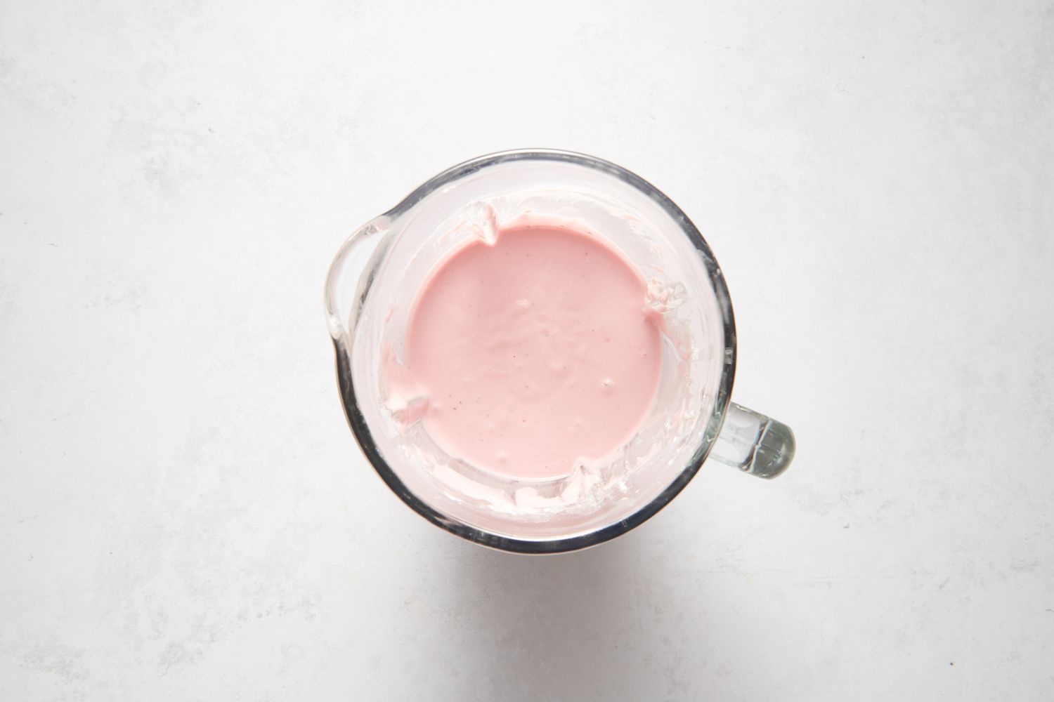 A blender pitcher with a batter made from oil, milk, eggs, condensed milk or syrup, food coloring, strawberries, miso, baking powder, sugar, and rice flour