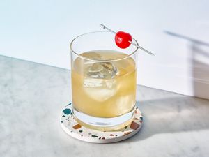 A whiskey sour garnished with a maraschino cherry