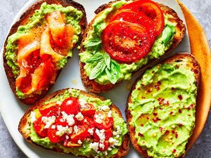 Four slices of avocado toast on a plate with various toppings