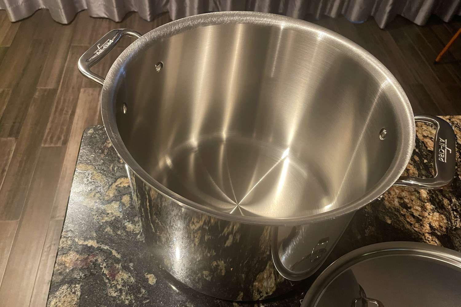 Empty All-Clad D3 12-quart stockpot on a dark marble counter
