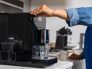 Person pressing button to dispense coffee from the Miele CM5300 Countertop Coffee System