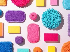 Multicolored sponges and cleaning pads arranged neatly on a white surface