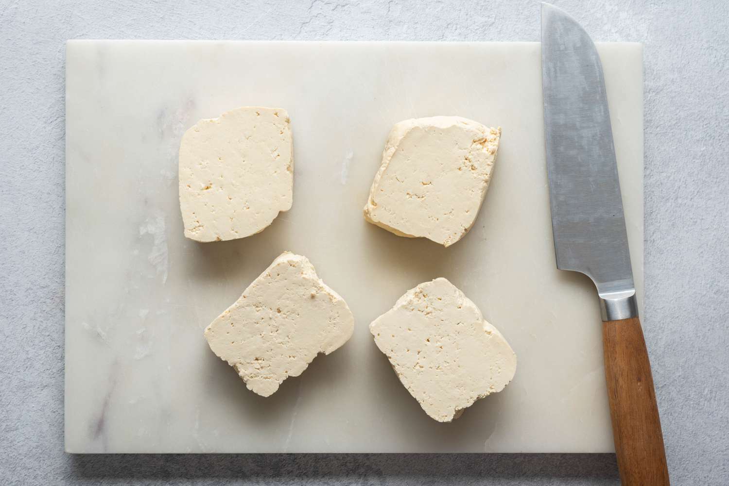 Tofu cut into four pieces on a cutting board 