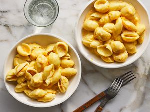 Two bowls of butternut squash macaroni and cheese with two glasses of sparkling water