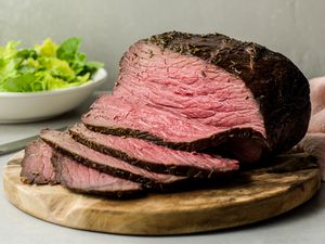 Marinated rump roast sliced on a wooden cutting board