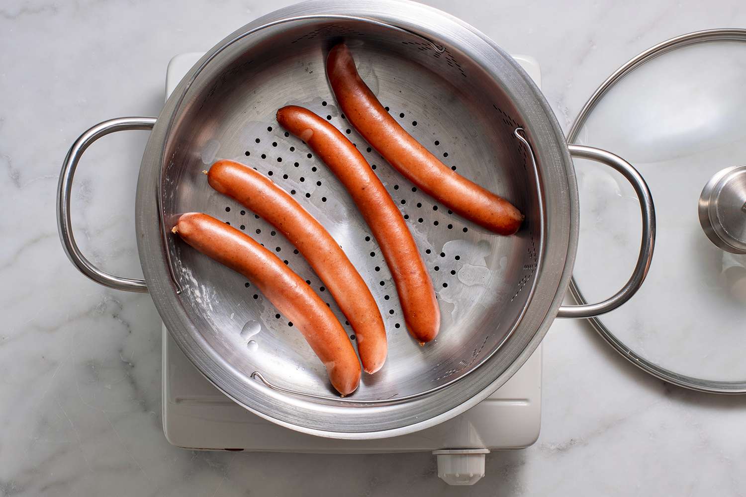 Cooked hot dogs in a steamer basket