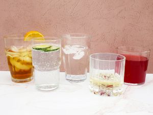 Assortment of drinking glasses we recommend displayed on a marble countertop while filled with various drinks