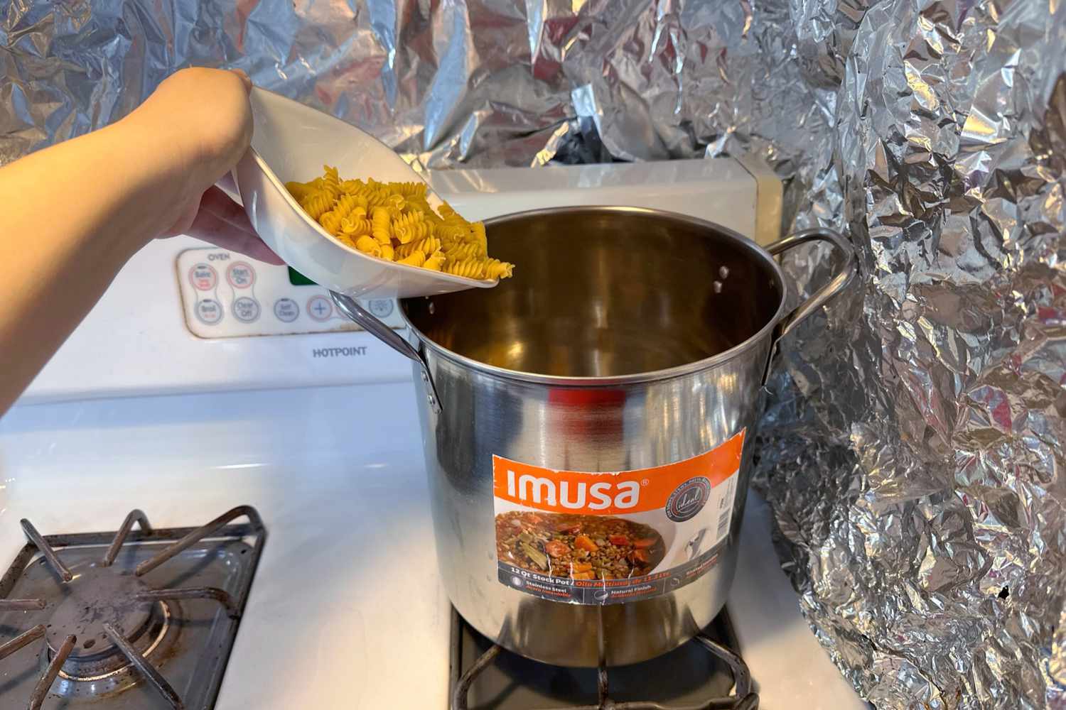 Dry pasta is poured into the IMUSA USA Stainless Steel Stock Pot, 12 Quart