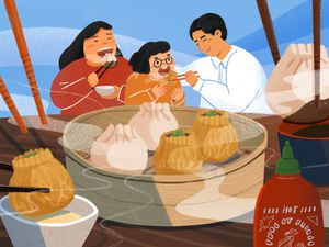 Three people eating dumplings at a table with chopsticks