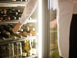 Woman reaching for bottle on wine in fridge