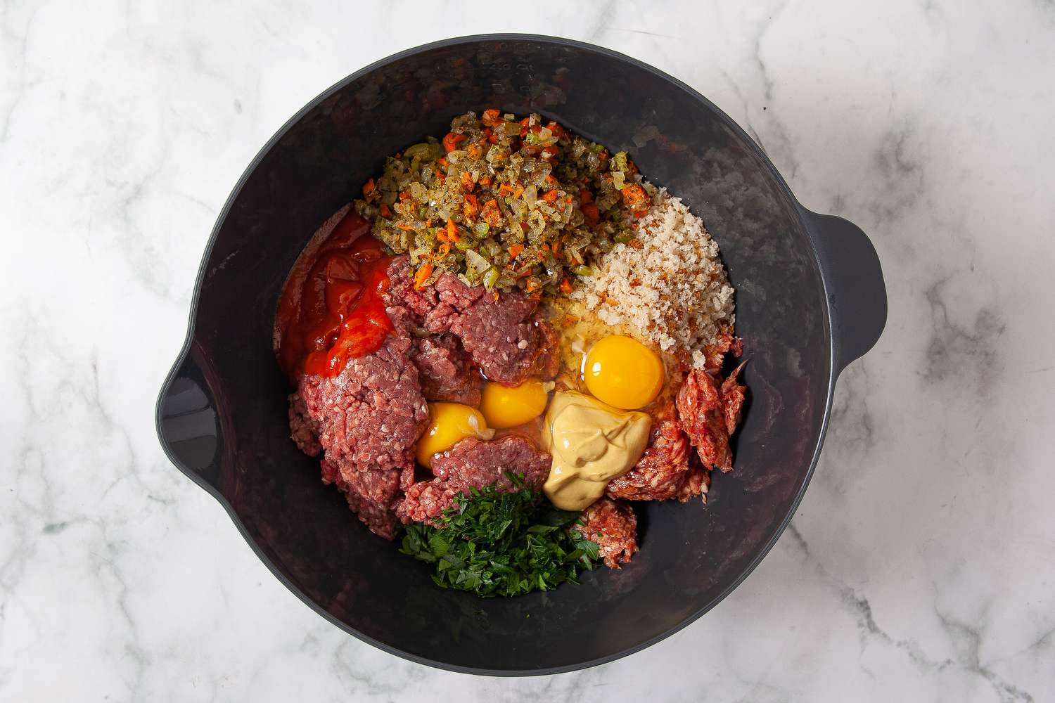 Ground beef, sausage, breadcrumbs, vegetables, eggs, parsley, and condiments in a bowl