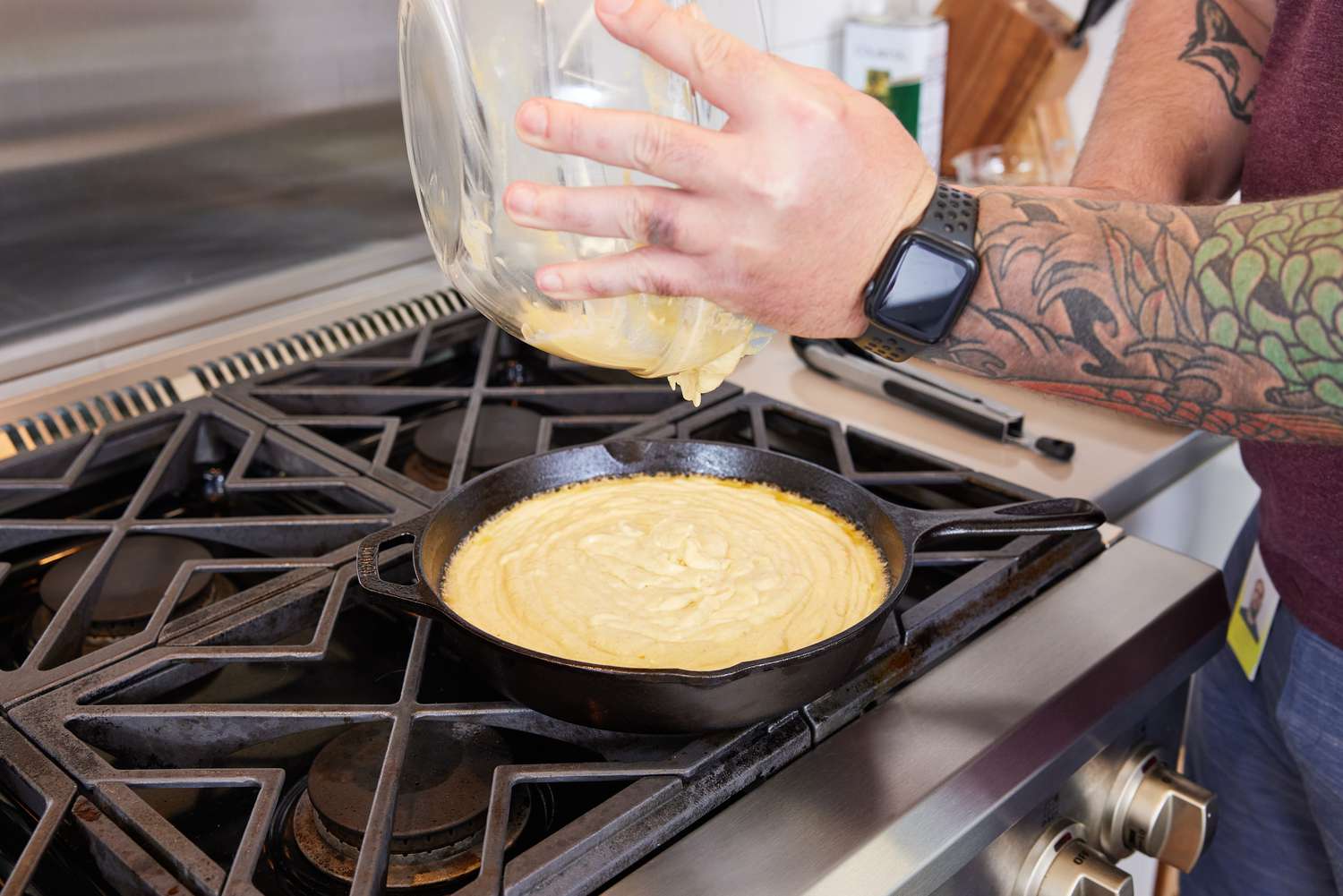 Hand pouring batter into a Lodge Cast Iron Skillet