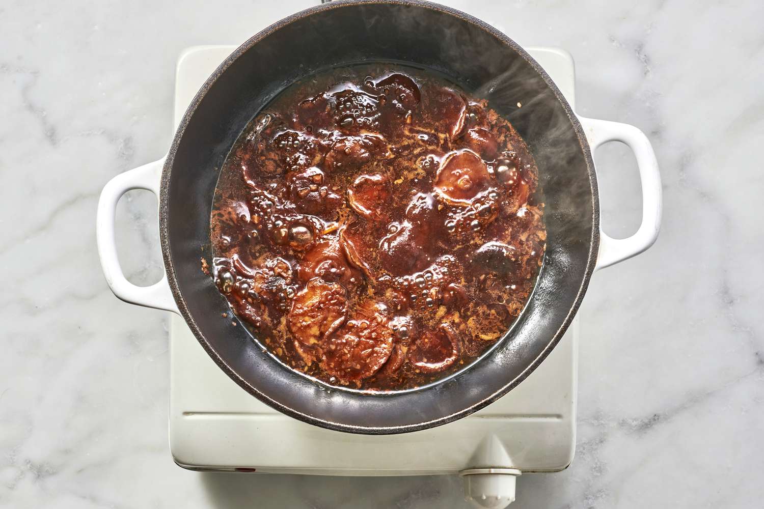 A pot of cooked shiitake mushrooms in a reduced braising sauce