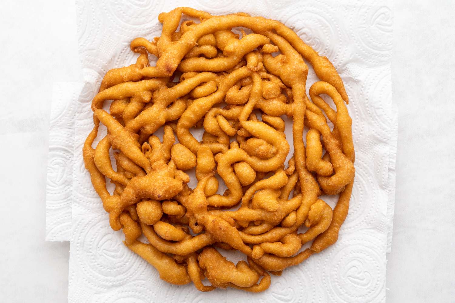 Golden brown funnel cake lying on paper towels