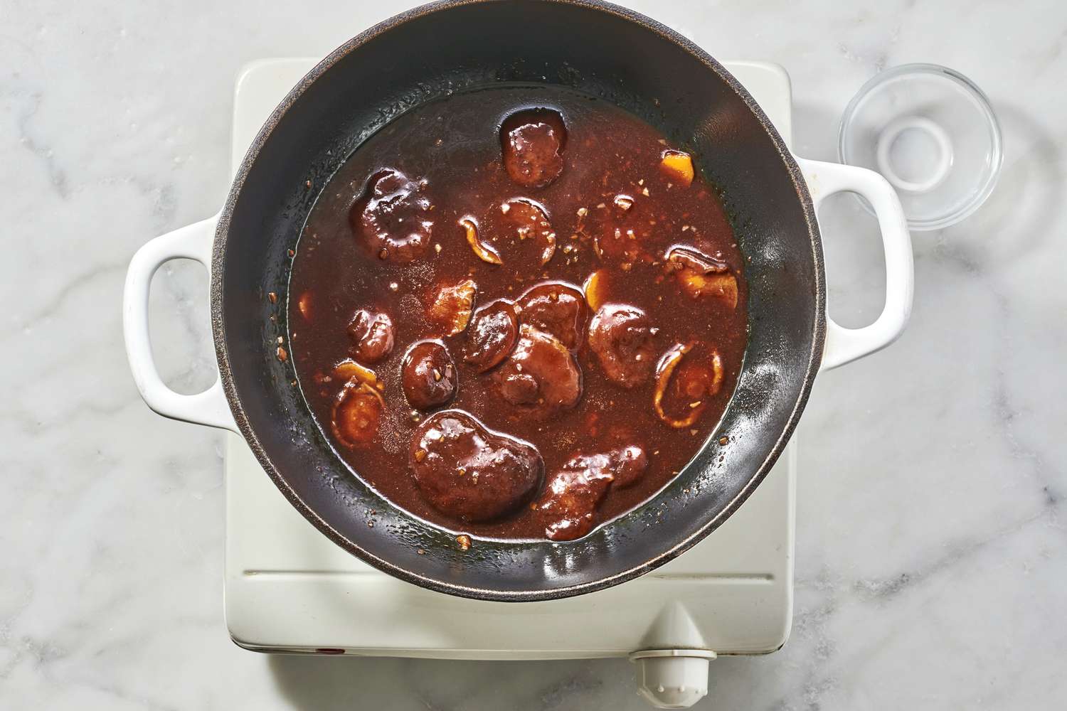 A pot of cooked shiitake mushrooms in a thickened braising sauce