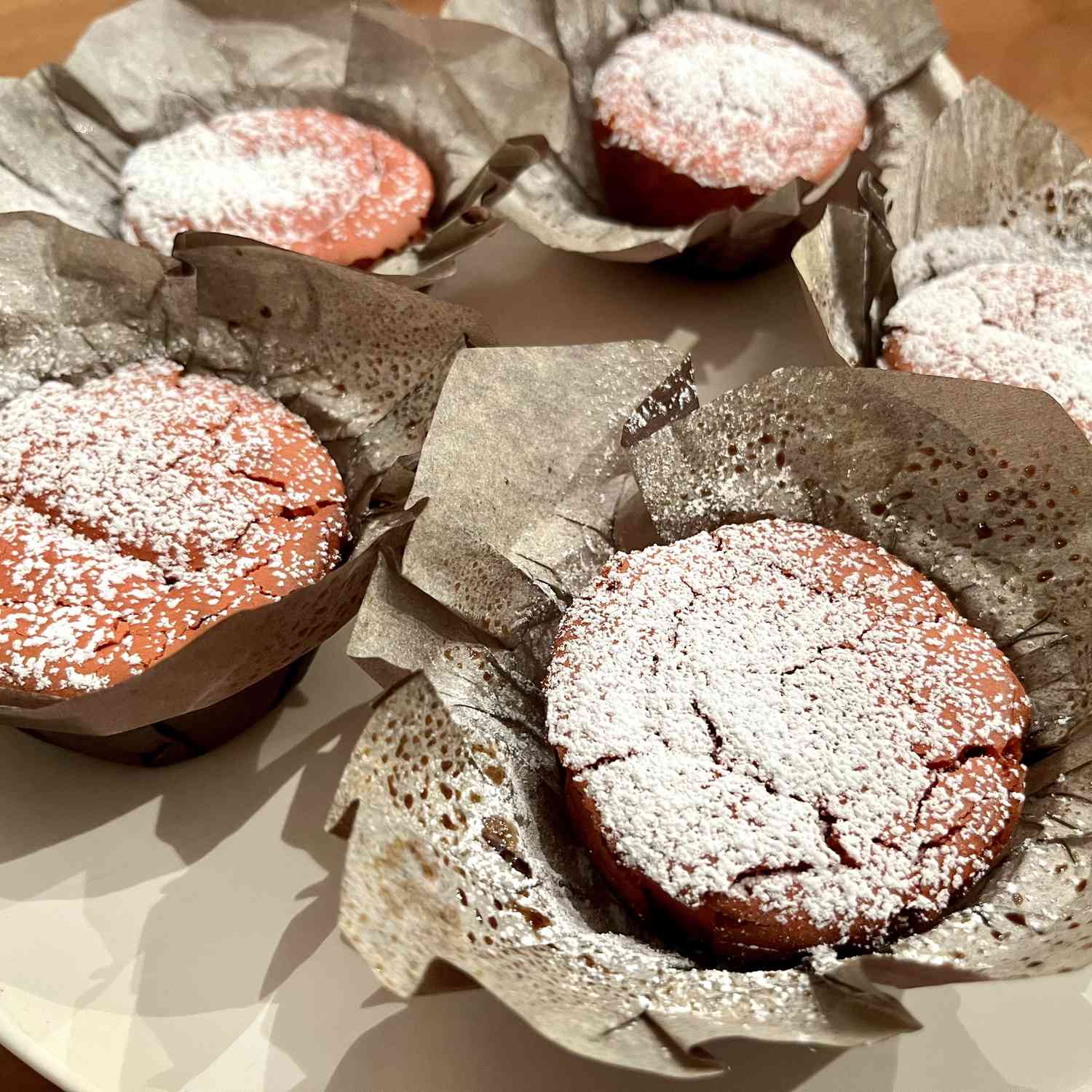 Pink muffins in paper muffin cups with powdered sugar dusted on top