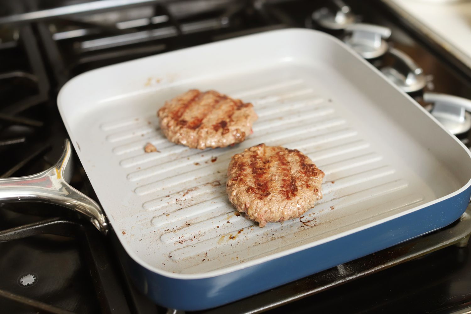 Small hamburgers cooking in the Caraway Griddle Pan