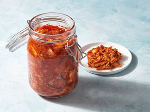 An open jar of mak kimchi next to a small plate with mak kimchi