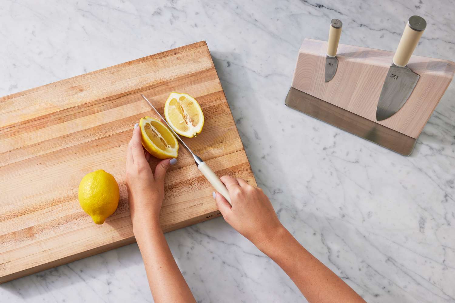 Person slicing lemons with Material The 8-Inch Knife on a wooden cutting board