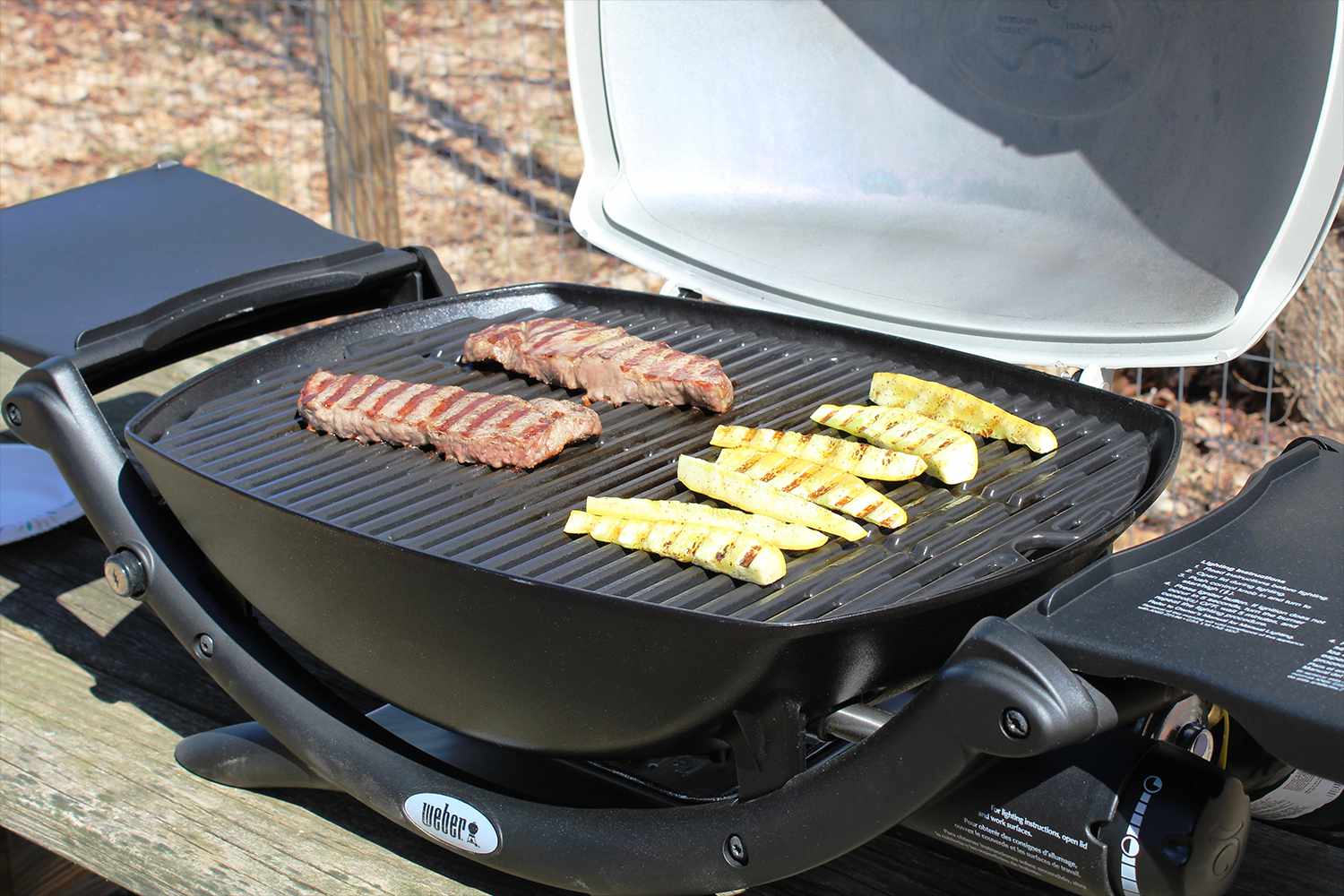 weber-q2200-propane-grill with steak and veggies grilling