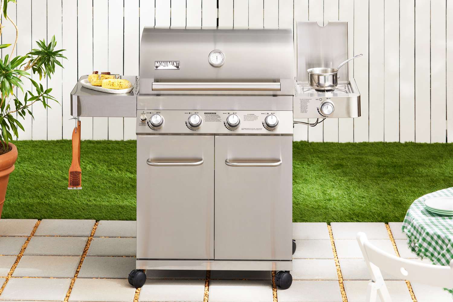 Monument Grills Stainless 4-Burner Propane Gas Grill displayed on pavers