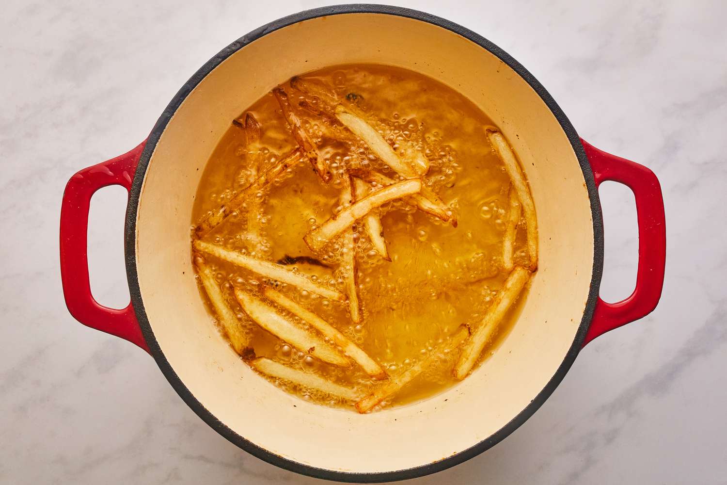 Frying potato fries in a pot of oil