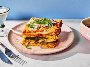 A serving of butternut squash lasagna on a plate, topped with fresh basil leaves