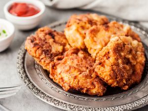 Southern fried chicken thighs on a plate with side of ketchup and sour cream and chive dip