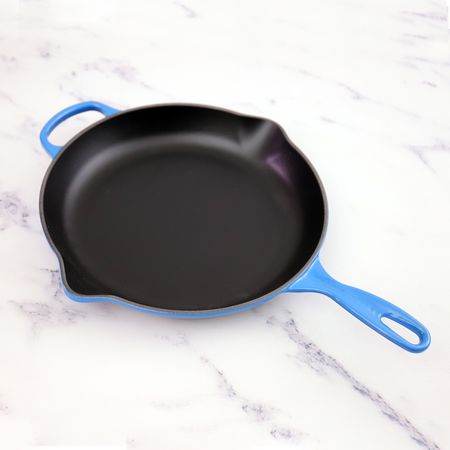 Blue Le Creuset Signature Skillet on a white marble surface 