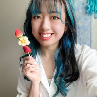 Sharon Hsu wearing a white button-down shirt and holding a skewer of strawberries