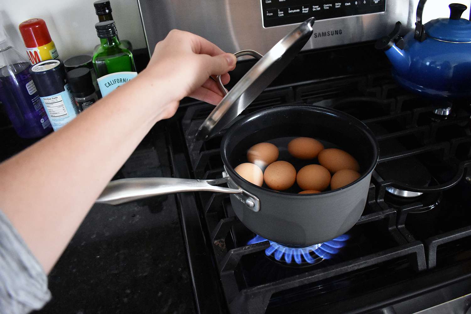 Person lifting the lid off of eggs boiling in a pot from the Cuisinart Green Gourmet Hard Anodized 12-Piece Cookware Set