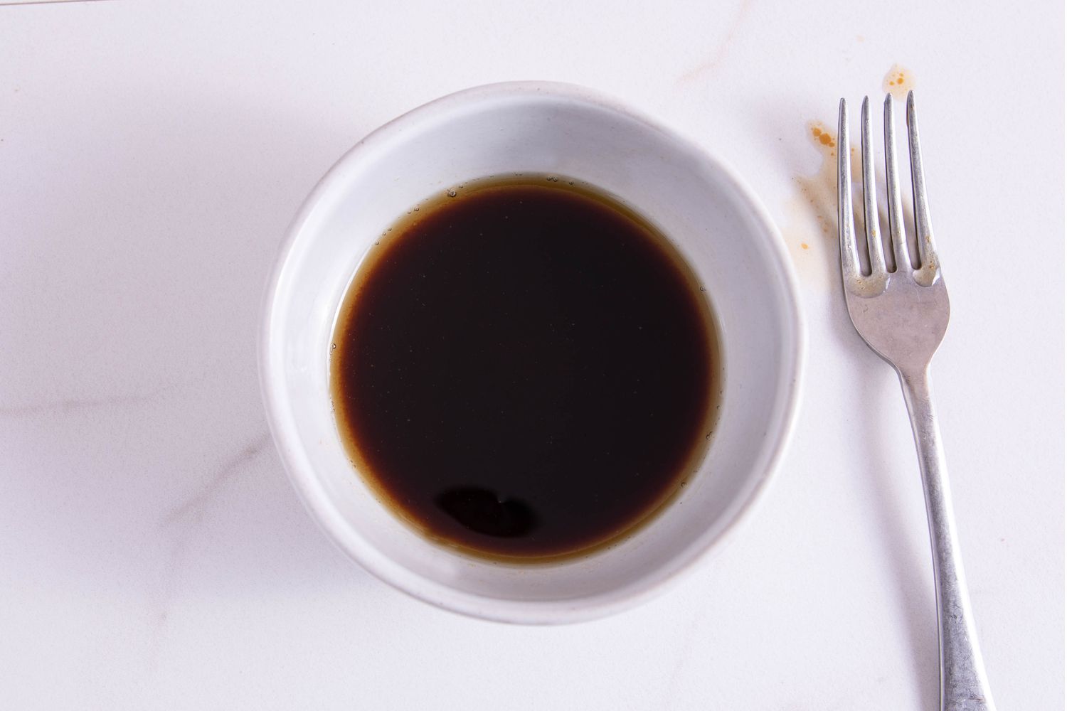 Small white bowl with sesame oil, soy sauce, vinegar, and sugar