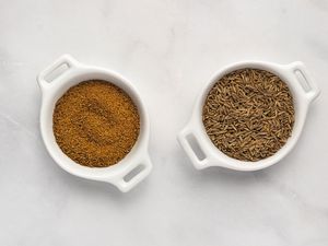 ground cumin and cumin seeds in bowls