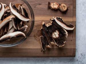 Sliced mushrooms on a cutting board and in a glass bowl 