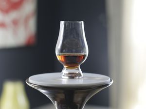 Glencairn Whisky Glass filled with whisky displayed on a round pedestal