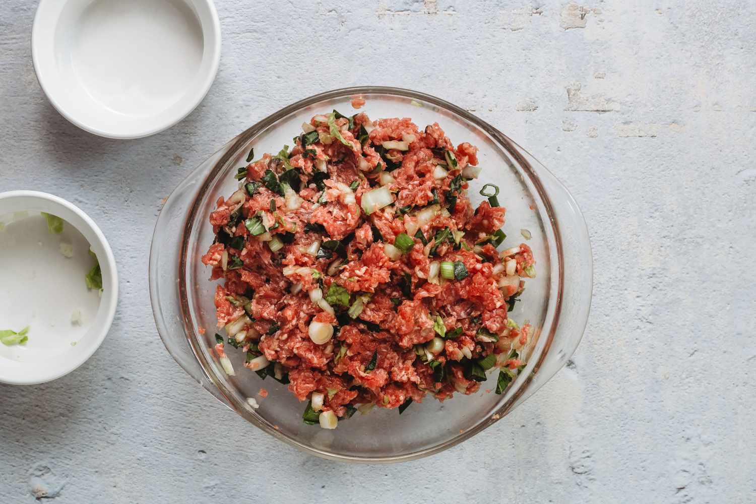 Dumpling filling ingredients combined in a glass bowl 