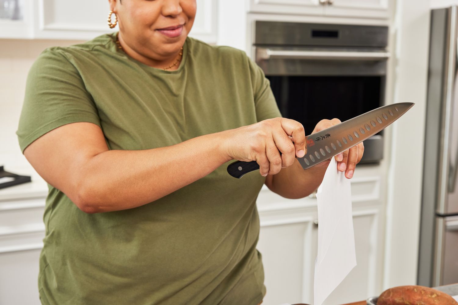 Woman slicing a piece of paper with a Mac Knife 8-Inch Hollow Edge Chef's Knife