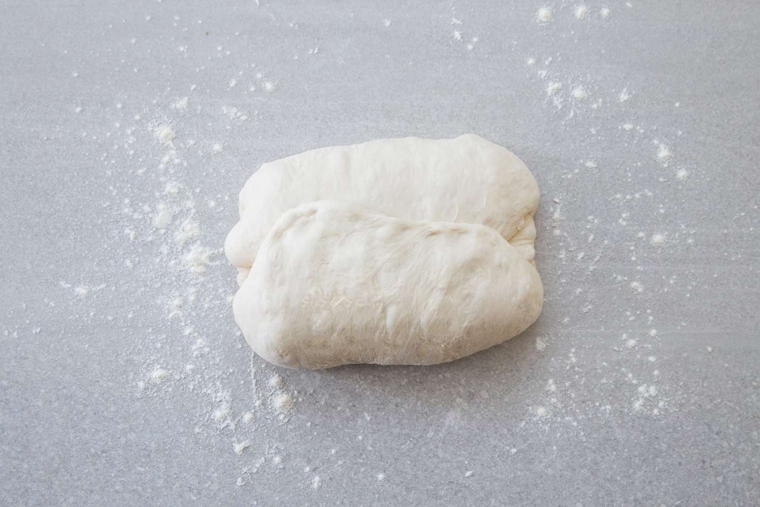 baguette dough folded into letter style on a floured counter