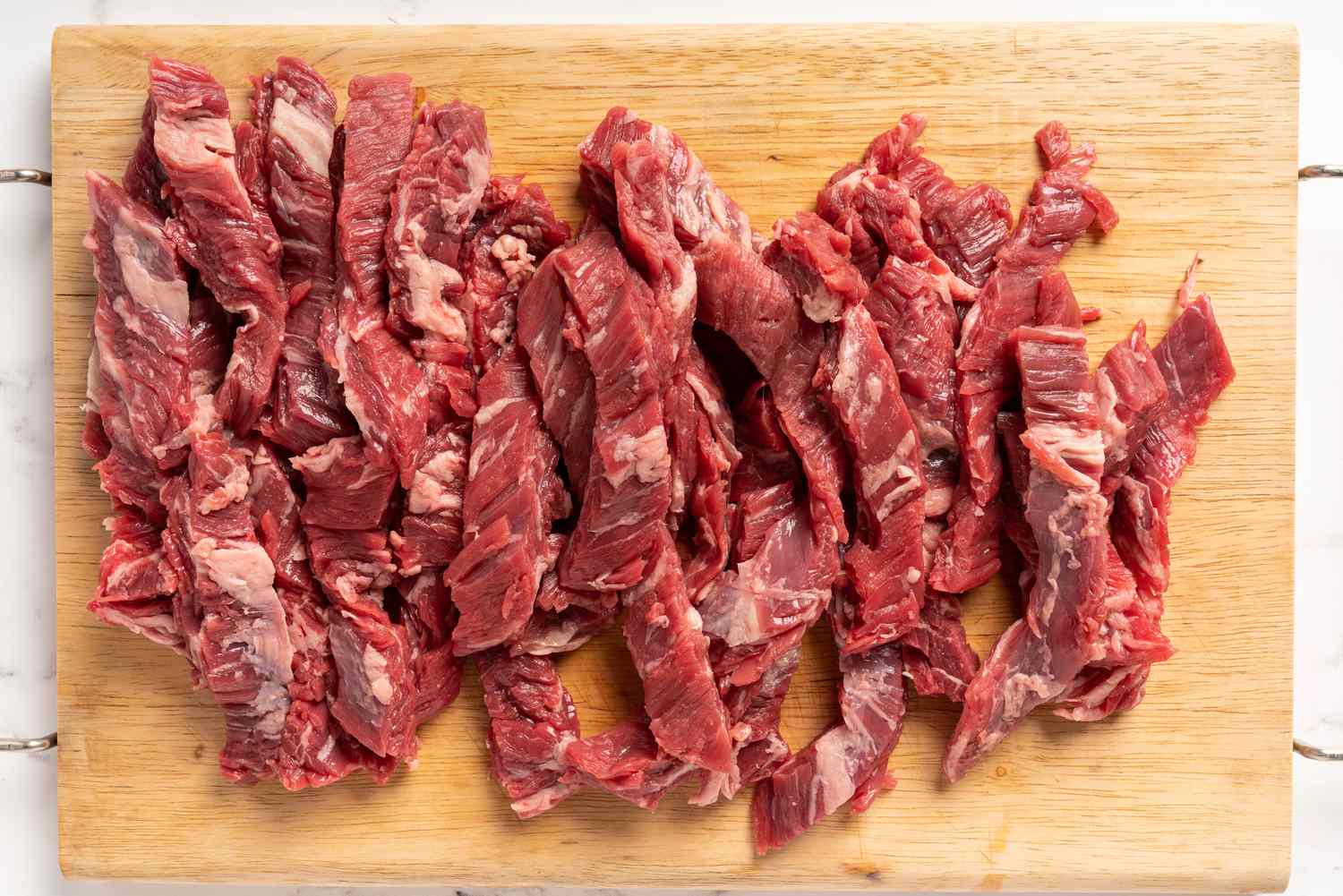 Steak cut across the grain into thin strips on a cutting board