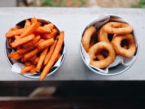 Sweet potato french fries and onion rings on a window sill