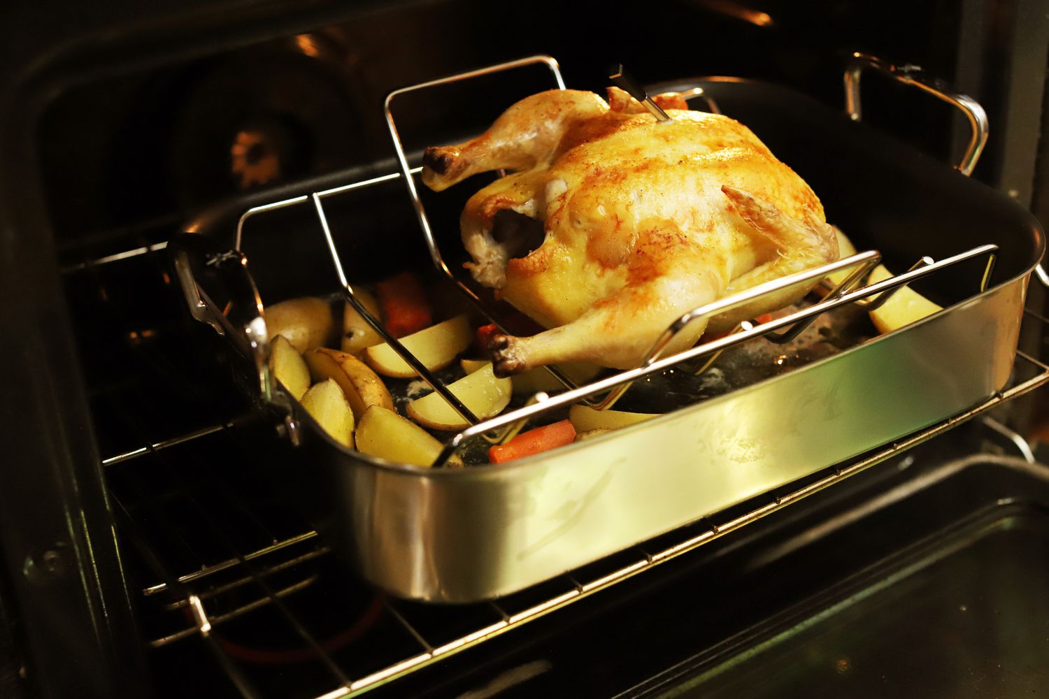 A roasted turkey in the Hestan Stainless Steel Nonstick Roaster's rack, with chopped vegetable underneath